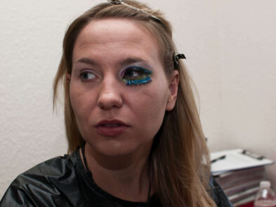Close-up of model Anne with blue glitter eye makeup being prepared for the Octopus Project.