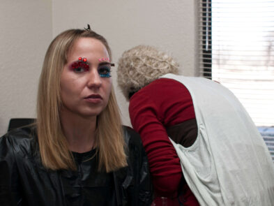 Model Anne with red gems and blue glitter eye makeup during a behind-the-scenes moment from the Octopus Project.