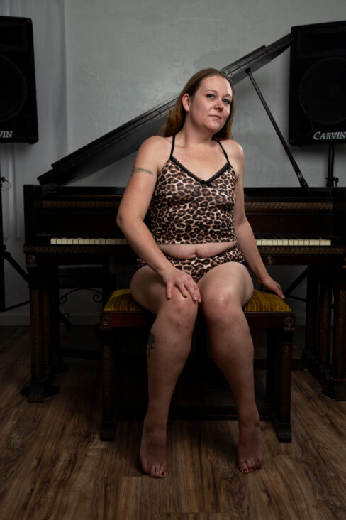 Portrait of Swisha Sweet seated on a piano bench wearing a leopard-print lounge set in front of a grand piano.