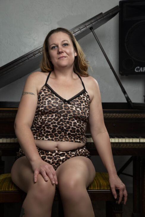 Close-up portrait of Swisha Sweet seated on a piano bench wearing a leopard-print lounge set in a studio.