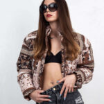 Shordy Kyy posing in a black lace top and embellished denim jeans against a light studio backdrop.