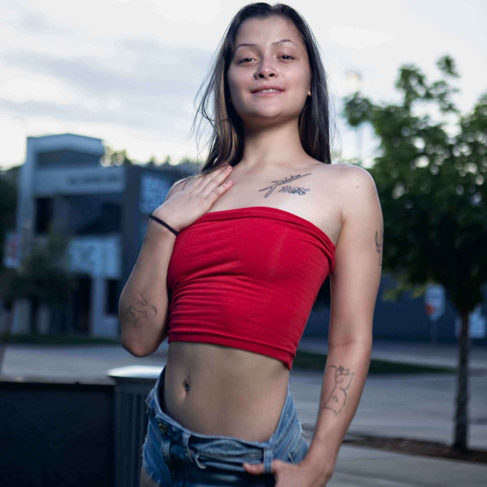 Portrait of Augustine Amasaman standing outdoors in a red tube top and denim shorts during a downtown Oklahoma City photoshoot.