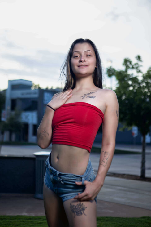 Portrait of Augustine Amasaman standing outdoors in a red tube top and denim shorts during a downtown Oklahoma City photoshoot.