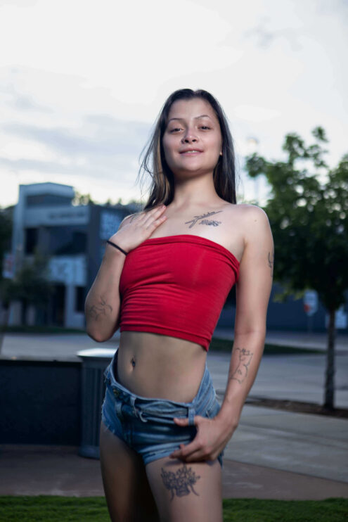 Portrait of Augustine Amasaman standing outdoors in a red tube top and denim shorts during a downtown Oklahoma City photoshoot.