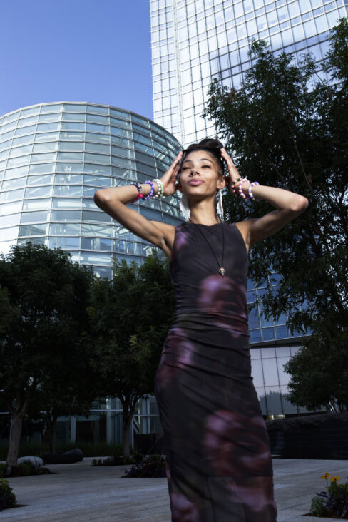 Bratzdoll posing in front of Devon Tower with modern glass architecture in downtown Oklahoma City.