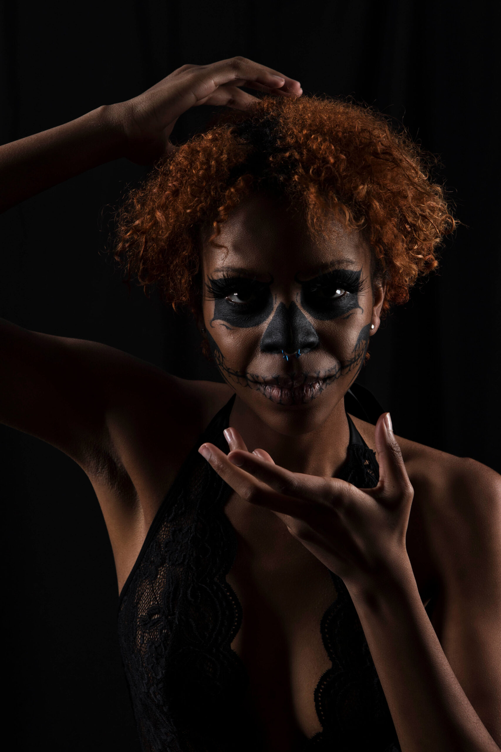 Saturn poses against a black background wearing dramatic black skull-inspired face makeup and black lace, framed by expressive hand gestures.