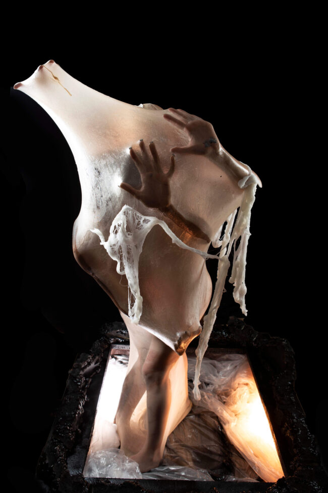 Two figures enclosed together beneath a stretched translucent membrane, their hands pressing outward as strands of white organic material hang across the surface.
