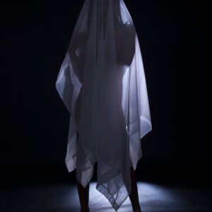 Model Kylie Hunter stands beneath translucent white fabric in a dark studio, dramatically backlit to create a mysterious silhouetted figure.