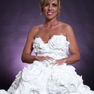 Angelique Pearson poses in an elaborate white whipped cream dress against a softly illuminated purple studio background during the Whipped Cream project.